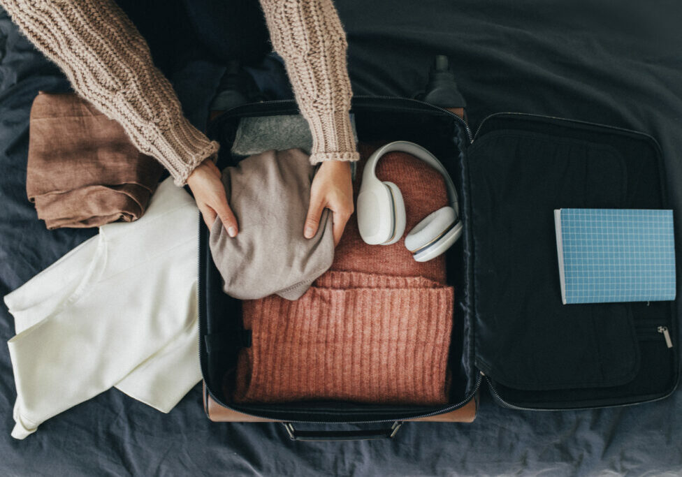 Happy traveller: a woman packing her clothes into a suitcase, getting ready for a trip.