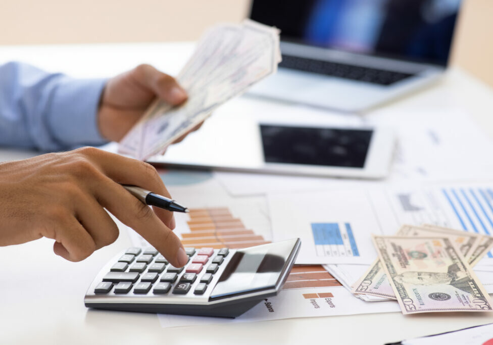 Calculator and money in business finance for budget, costs or expenses at the office desk
