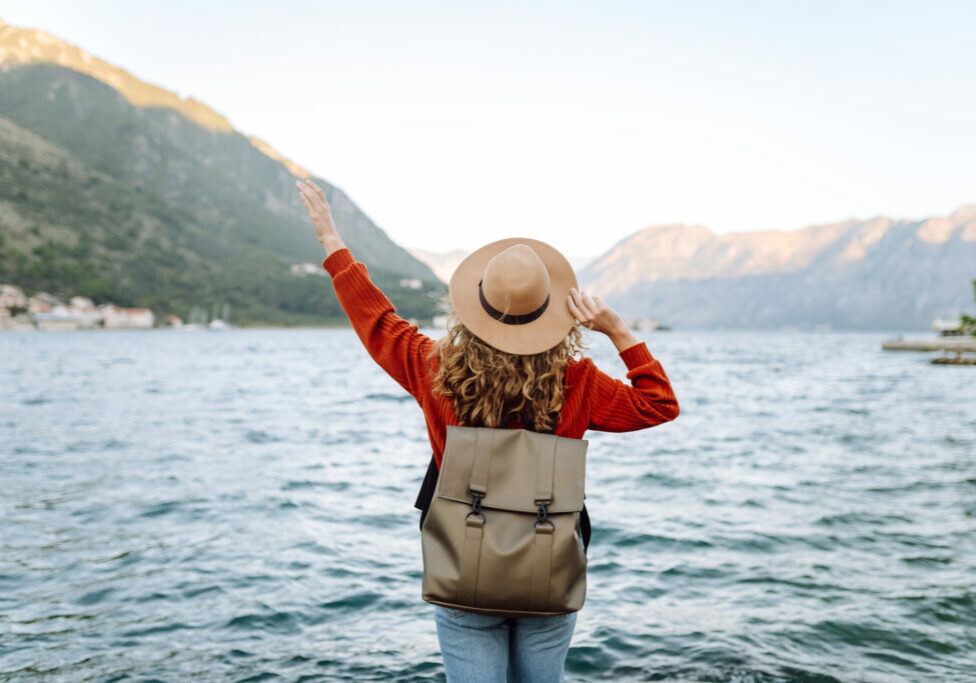 Back view young woman tourist admiring view of colorful the view of the city and view of the mountain bay. Lifestyle, vacation, rest, active life.