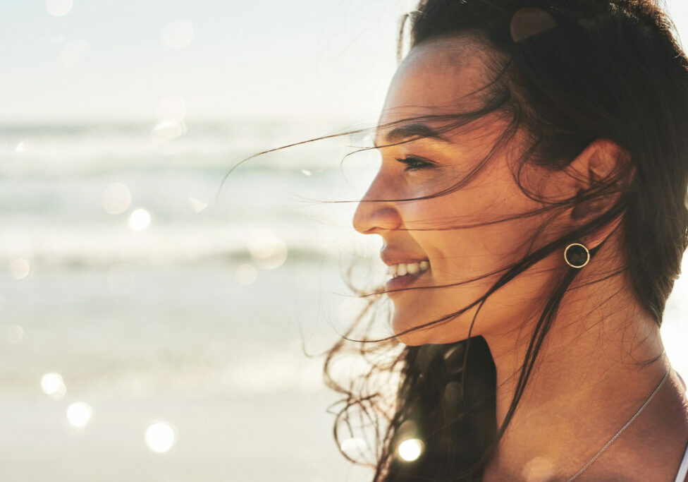 Shot of a beautiful young woman enjoying a summer’s day at the beach