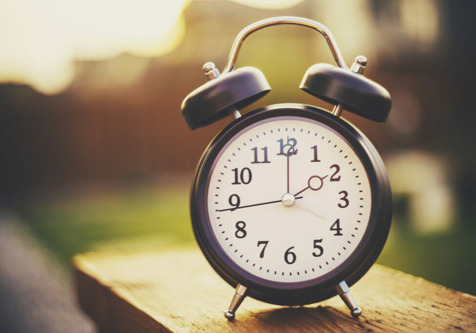 Daylight savings time. Retro clock outdoors with warm glow